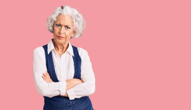 Senior grey-haired woman wearing casual clothes skeptic and nervous, disapproving expression on face with crossed arms. negative person.  clipart
