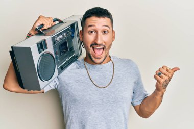 Elinde teyp tutan yakışıklı adam, müzik dinliyor başparmağını yana kaldırıyor ve ağzı açık gülümsüyor. 