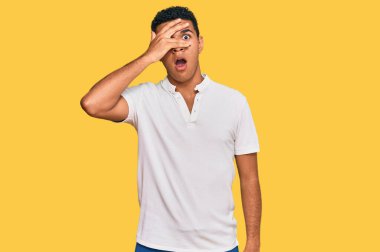 Gündelik kıyafetler giyen genç Arap adam şok içinde yüzünü ve gözlerini kapayarak utanmış ifadesiyle parmaklarının arasından bakıyor.. 