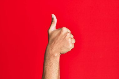 Kafkasyalı beyaz adamın kolları kırmızı izole edilmiş arka planda başarılı onay jestleri yapıyor. Başparmaklar yukarı, onaylama ve pozitif sembol ile. 