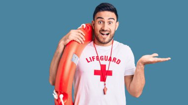 Cankurtaran üniforması giyen genç yakışıklı adam zaferi mutlu bir gülümsemeyle kutluyor ve ellerini kaldırarak kazanan yüz ifadesi takınıyor. 