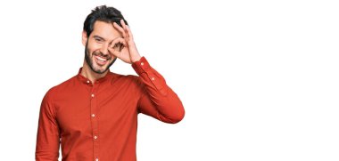 Gündelik kıyafetler giyen genç İspanyol adam el hareketleriyle gülümsüyor ve mutlu yüzüyle parmaklarından bakıyor.. 