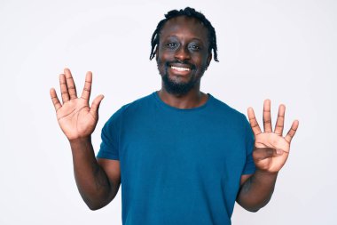 Saçları örgülü genç Afro-Amerikan bir adam 9 numarayı gösterip gösterirken kendinden emin ve mutlu bir şekilde gülümsüyor.. 