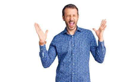 Gündelik kıyafetler giyen genç, çılgın ve çılgın başarıyı kutlayan kollarını kaldırmış, gözlerini kapatmış heyecanlı çığlıklar atan yakışıklı bir adam. Kazanan konsept 