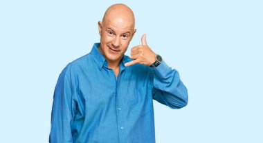 Orta yaşlı, kel, sıradan kıyafetler giyen, gülümseyen, el ve parmaklarıyla telefonla konuşan bir adam. iletişim kavramları. 