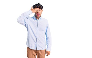 Genç İspanyol gömlekli adam şok içinde yüzünü ve gözlerini kapayarak utanmış ifadesiyle parmaklarının arasından bakıyor.. 