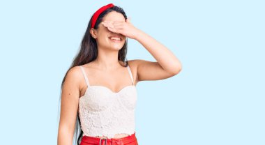 Zarif görünümlü esmer kız. Gülümsüyor ve elleri yüzün üzerinde gülüyor. Şaşırtmak için gözleri örtüyor. kör kavram. 