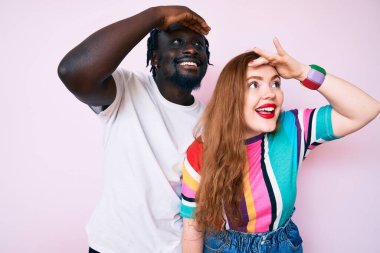 Irklar arası çiftler gündelik giysiler giyip çok mutlu ve gülümsüyorlar başlarını kaldırıp uzaklara bakıyorlar. arama kavramı. 