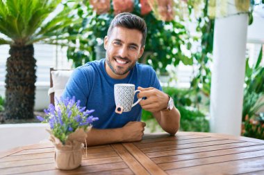 Genç İspanyol adam terasta masada oturmuş çay içiyor..