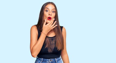 Gündelik kıyafetler giyen genç İspanyol kadın, elleri çenesinde, inanamama, şaşkınlık ve şaşkınlık dolu bir ifade takınıyor. 