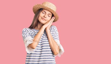 Güzel beyaz kadın yaz şapkası takıp uyuyor. Yorgun düşler görüyor, ellerle poz veriyor ve gözleri kapalı gülümsüyor.. 