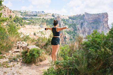 Genç İspanyol kadın spor giyim kuşamı giyiyor. Güzel uçurumun kenarında kolları açık nefes almak.
