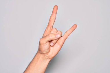 Beyaz arka planda parmaklarını gösteren beyaz tenli bir gencin eli. Rock 'n Roll sembolü, müstehcen boynuzlar gösteriyor.