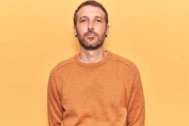 Yüzünde ciddi bir ifade olan sıradan kıyafetler giyen genç yakışıklı bir adam. Basit ve doğal bir şekilde kameraya bakıyorsun.. 