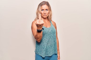 Middle age caucasian blonde woman wearing sportswear showing middle finger, impolite and rude fuck off expression 