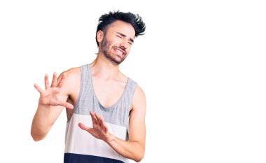 Gündelik kıyafetler giyen genç İspanyol adam tiksinti ifadesi takındı, tiksinti tepkisi yüzünden tiksinti ve korku dolu bir ifade takınıyordu. Eller havada. 