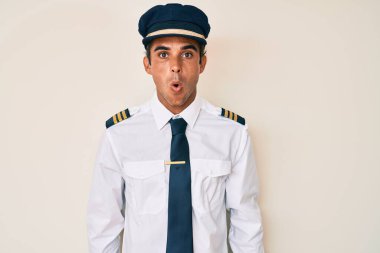 Uçak pilotu üniforması giyen genç İspanyol adam şaşkınlık ve şaşkınlık ifadesi, korku ve heyecanlı yüz ifadesiyle dehşete düşmüş ve şok olmuştu.. 