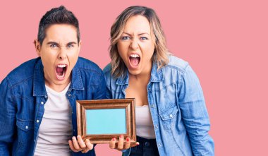 Elinde boş bir çerçeve olan kızgın ve kızgın iki kadın öfkeli ve öfkeliler, öfkeyle bağırıyorlar. öfke ve agresif konsept. 