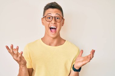 Gündelik kıyafetler ve gözlük takan genç İspanyol çocuk zaferi mutlu bir gülümsemeyle kutluyor ve kazanan yüz ifadesi kaldırıyor. 