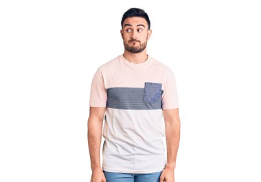 Gündelik kıyafetler giyen genç yakışıklı adam gülümseyerek yan tarafa bakıyor ve düşünüyor.. 