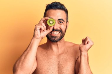 İspanyol asıllı genç üstsüz bir adam elinde kivi tutarak gururla bağırıyor zaferi ve başarıyı kutluyor. 