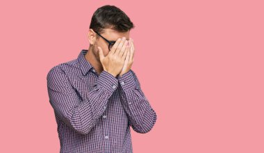 Yakışıklı beyaz adam, günlük kıyafetler ve ağlarken suratını ellerle kapatan üzgün yüzlü gözlük takıyor. depresyon kavramı. 