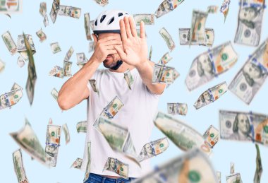 Bisiklet kaskı takan genç yakışıklı adam elleriyle gözlerini kapatıyor ve üzgün ve korku ifadeleriyle jest yapıyor. utangaç ve olumsuz kavram.