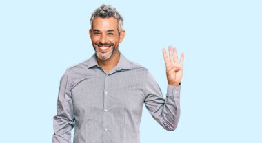 Orta yaşlı, gri saçlı, günlük kıyafetler giyen, dört numarayı gösteren ve gülümseyen, kendinden emin ve mutlu bir adam.. 