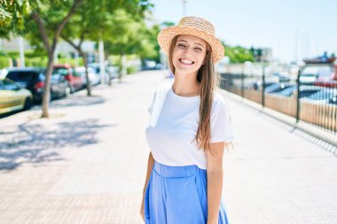 Genç sarışın kadın tatilde gülümsüyor. Mutlu bir şekilde caddede yürüyor.