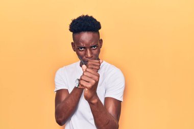 Genç, Afro-Amerikalı, günlük kıyafetler giymiş, yumruk savunma hareketleriyle dövüşmeye hazır, kızgın ve üzgün yüzlü, sorundan korkan. 