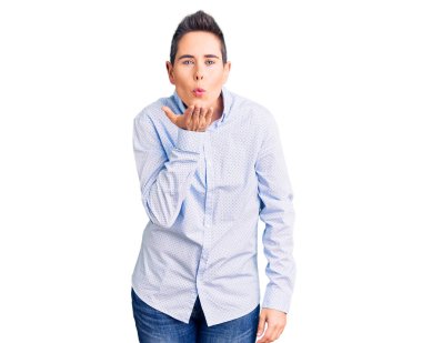 Kısa saçlı genç bir kadın iş kıyafetleri içinde kameraya bakıyor ve havada bir öpücük savuruyor. Güzel ve seksi. aşk ifadesi. 