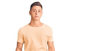 Gündelik kıyafetler giyen genç yakışıklı adam yüzünde ciddi bir ifadeyle rahatlamış. Basit ve doğal bir şekilde kameraya bakıyorsun.. 