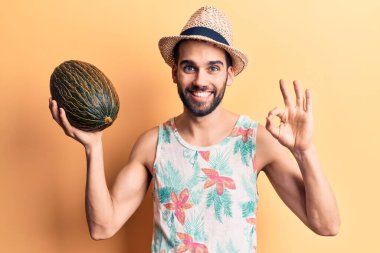 Sakallı, yaz şapkalı ve tişörtlü yakışıklı bir adam kavun tutuyor. Parmaklarıyla imza atıyor, gülümsüyor. 