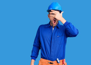 Genç, yakışıklı, işçi üniforması giyen, kasketli, iyi bir jest yapan, şaşkın yüzlü, gözleriyle parmaklarından bakan bir adam. İnançsız ifade. 