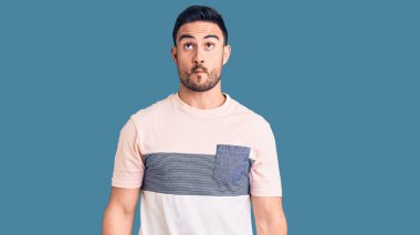 Gündelik kıyafetler giyen genç yakışıklı adam dudaklarıyla balık suratı yapıyor, çılgınca ve komik bir jest. Komik ifade. 