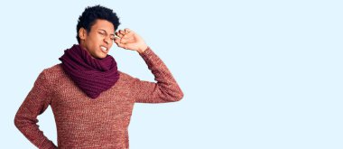 Genç Afro-Amerikan adam, günlük kışlık süveter ve atkı giymiş, yorgun ve rahat, uykulu ve sabahın erken saatleri için esniyor. 