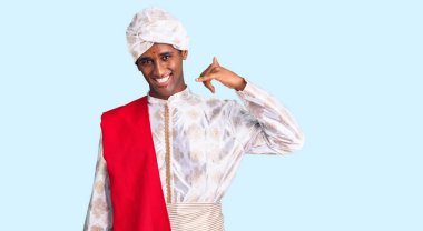 Gelenek giyinmiş Afrikalı yakışıklı bir adam Sherwani sari elbisesi giyiyor telefonla el ve parmak hareketleriyle gülümsüyor telefonda konuşuyor gibi. iletişim kavramları. 