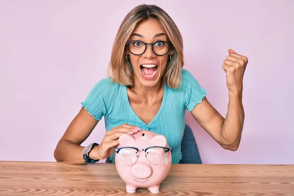 Beautiful Caucasian Woman Holding Piggy Bank Glasses Screaming Proud Celebrating — Stock Photo, Image