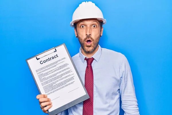 Jovem Homem Bonito Vestindo Arquiteto Hardhat Segurando Documento Contrato Assustado — Fotografia de Stock