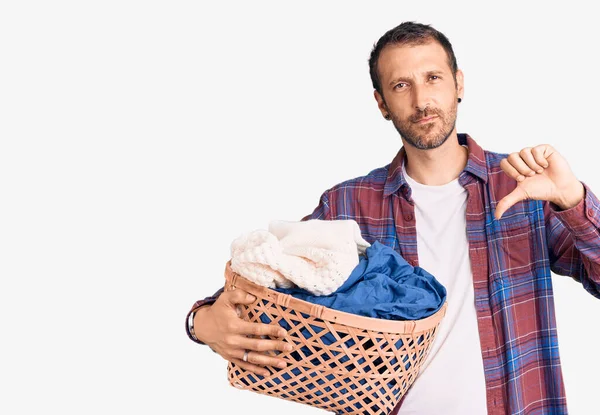 Jovem Homem Bonito Segurando Cesta Roupa Com Rosto Irritado Sinal — Fotografia de Stock