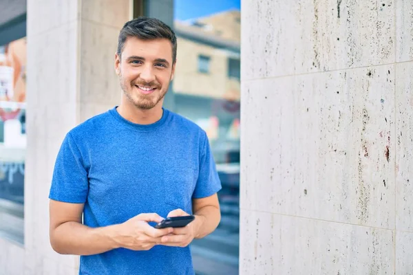 若い白人男性が市内のスマートフォンを使って笑顔で幸せ — ストック写真