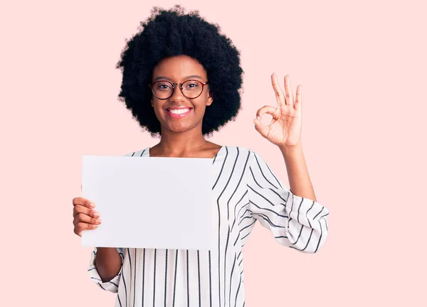 Młoda Afroamerykanka Trzyma Pusty Papier Robiąc Znak Palcami Uśmiechając Się — Zdjęcie stockowe