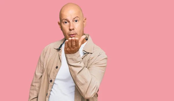 Middle age bald man wearing casual clothes looking at the camera blowing a kiss with hand on air being lovely and sexy. love expression.