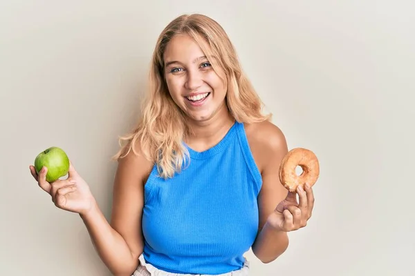 Junge Blonde Mädchen Mit Grünem Apfel Und Donut Feiern Verrückt — Stockfoto