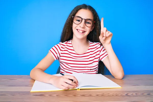 Bonita Menina Hispânica Sentada Mesa Escrevendo Livro Surpreso Com Uma — Fotografia de Stock