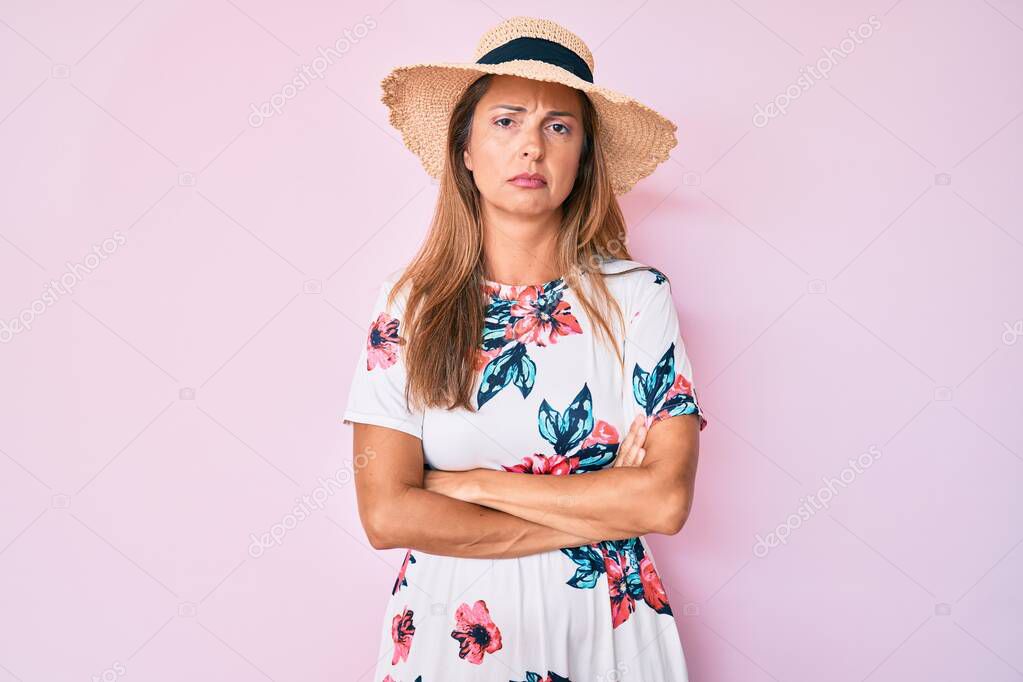 Middle age hispanic woman wearing summer hat skeptic and nervous, disapproving expression on face with crossed arms. negative person. 