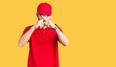 Sakallı yakışıklı, teslimat üniforması giyen, reddedilme ifadesi takınan ve negatif işaret veren genç adam. 