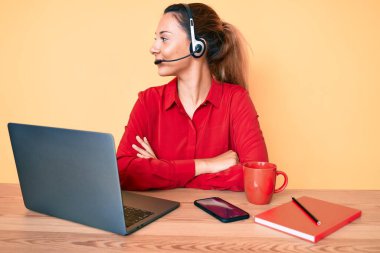 Çağrı merkezindeki operatör kulaklığı takan genç esmer kadın yan tarafa bakıyor, rahat profil pozu veriyor kendine güveni tam bir gülümsemeyle.. 