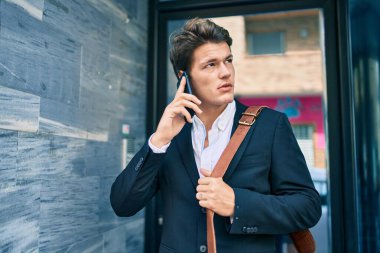 Kafkasyalı genç iş adamı ciddi bir ifadeyle şehirdeki akıllı telefondan konuşuyor..