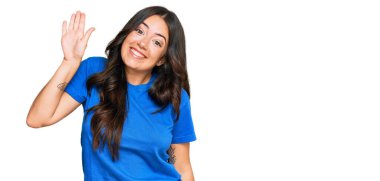 Güzel, esmer, gündelik giysiler içinde genç bir kadın merhaba diyor mutlu ve gülümsüyor, dostça bir hoş geldin jesti. 